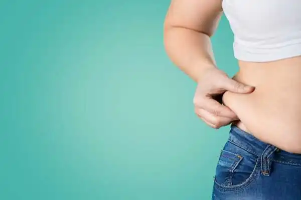 Image of woman pinching her love handles to show weight gain Thame